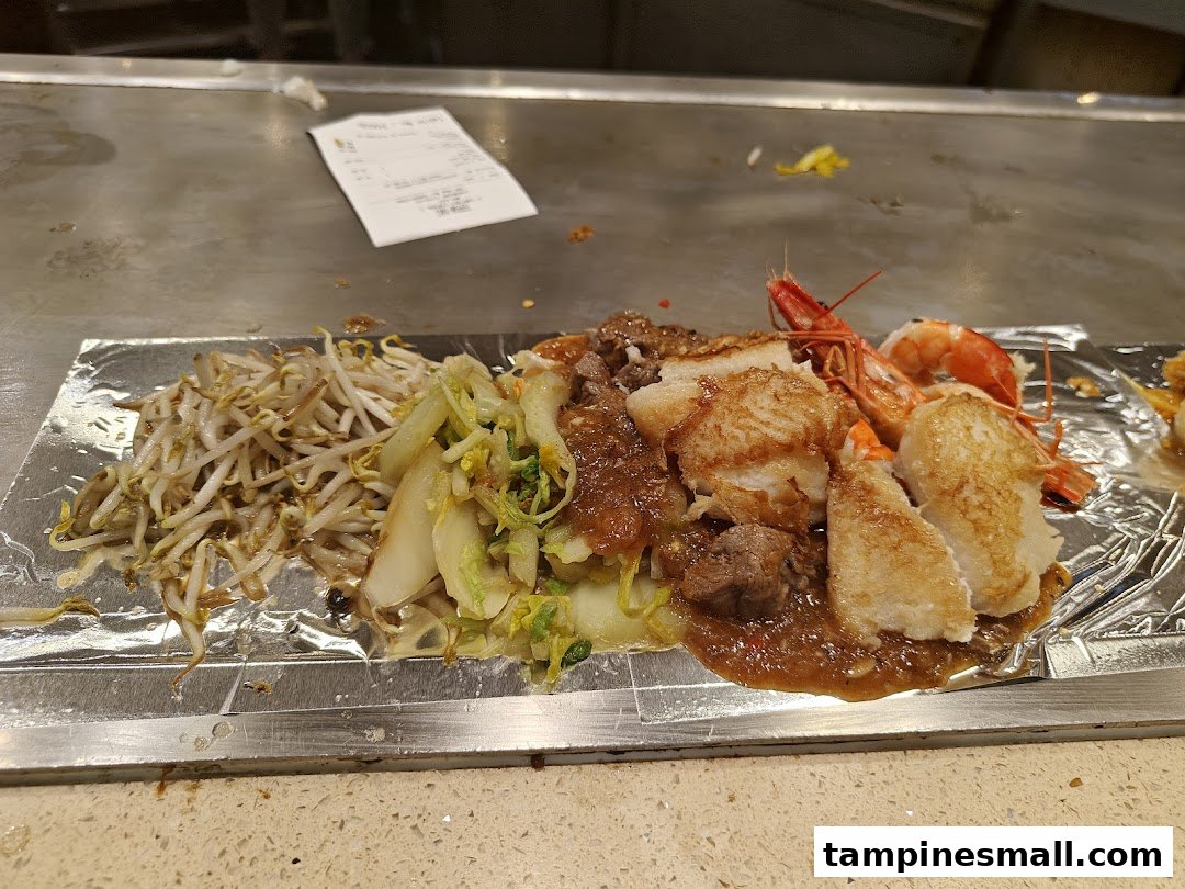 A delicious teppan-yaki meal with seafood, meat, and vegetables served on a hot grill.