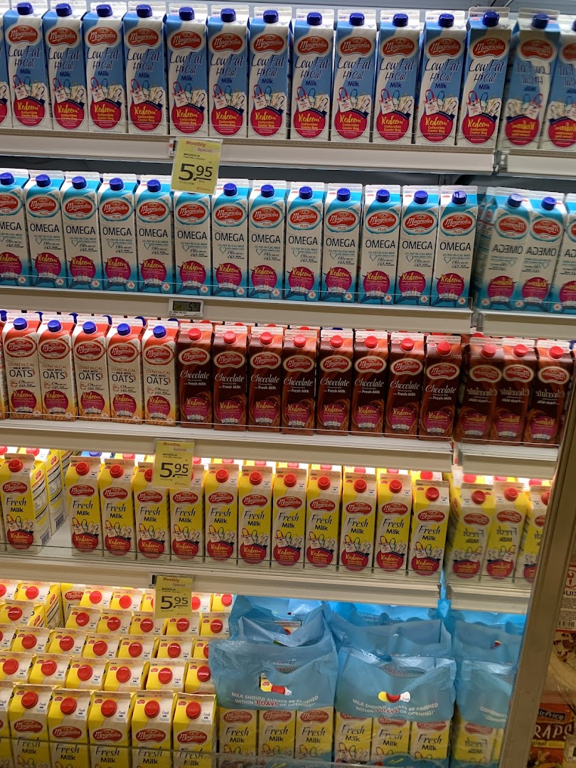 A refrigerated display shelf filled with various Magnolia brand milk cartons in a supermarket.