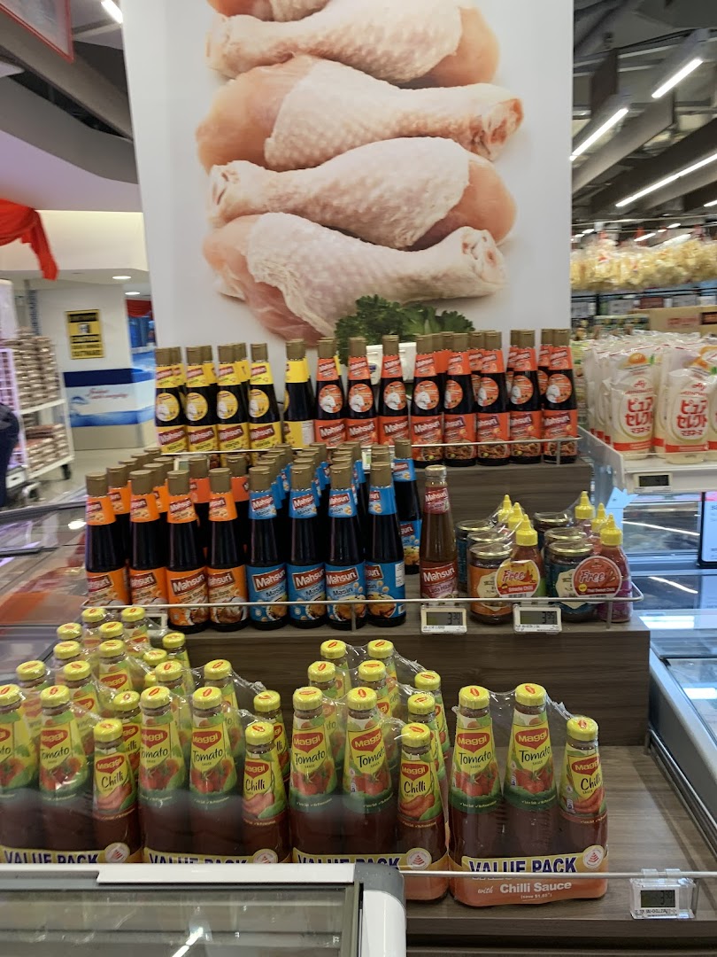 A supermarket aisle featuring a display of various sauces, including Maggi and Mahsuri brands, with a large chicken poster.