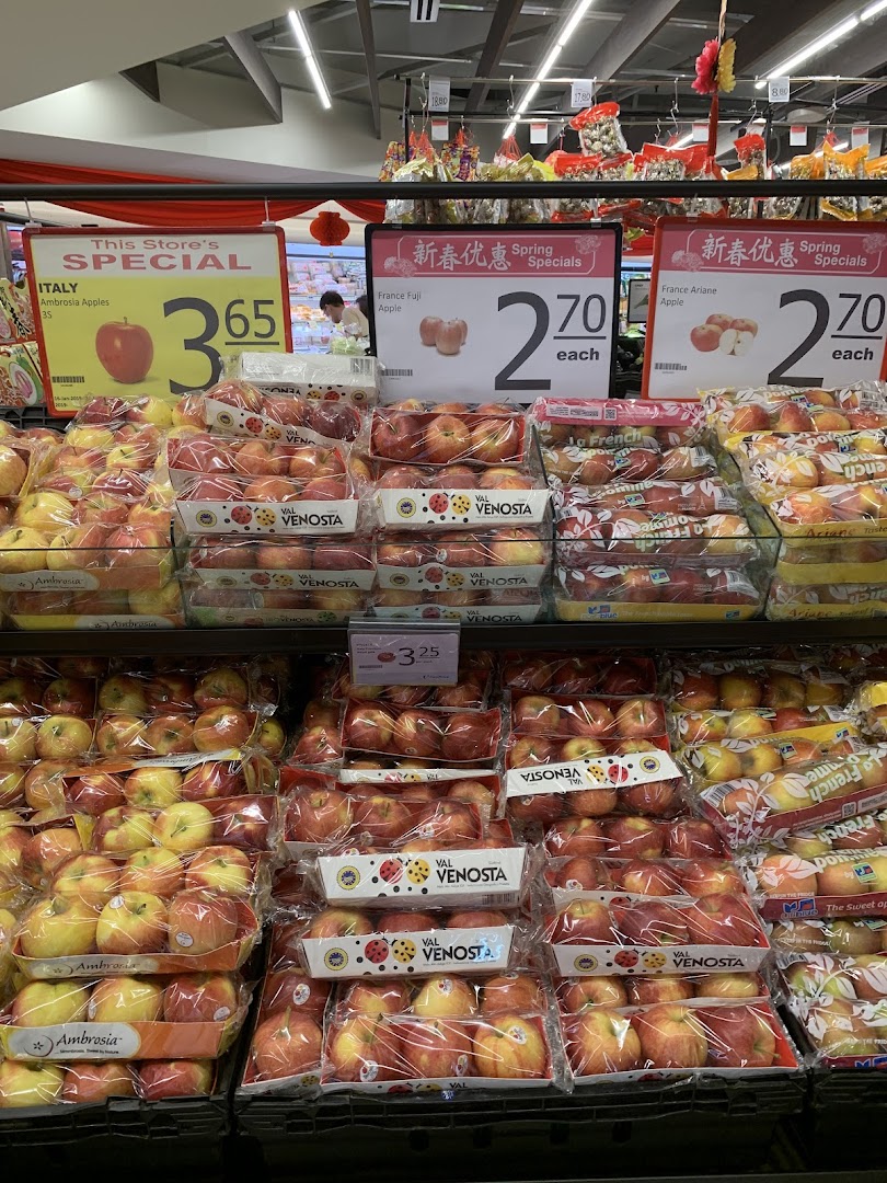A vibrant display of various packaged apples with special offer signs at FairPrice Tampines Mall.
