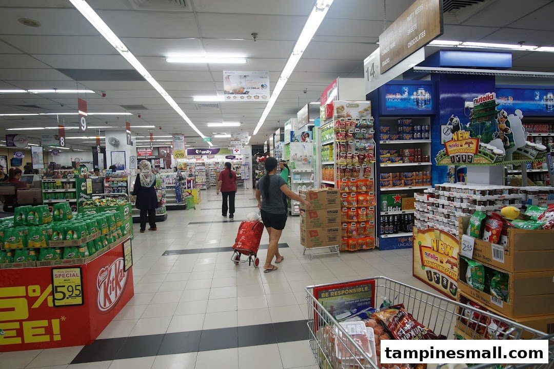 A bustling supermarket aisle at FairPrice Tampines Mall, showcasing diverse products and shoppers.