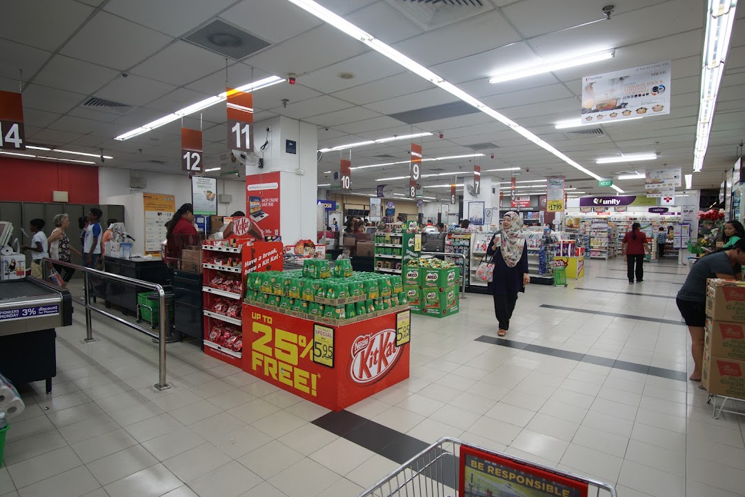 A bustling interior view of FairPrice Tampines Mall, showcasing wide aisles, checkout counters, and product displays.