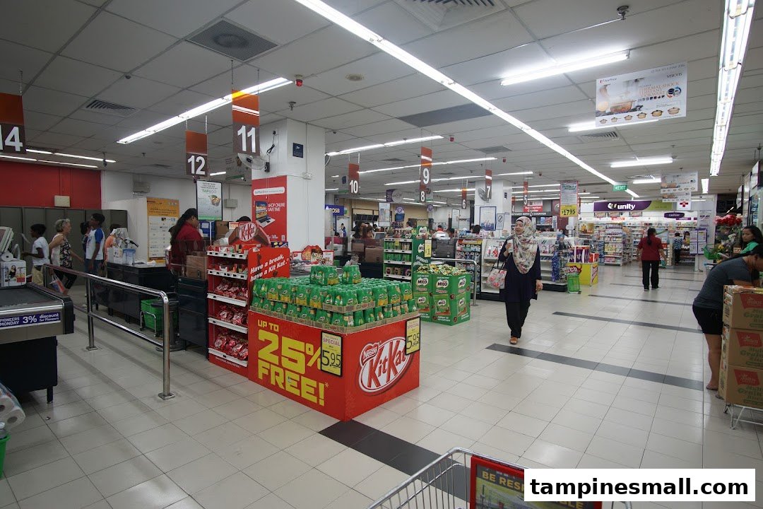 A bustling interior view of FairPrice Tampines Mall, showcasing wide aisles, checkout counters, and product displays.