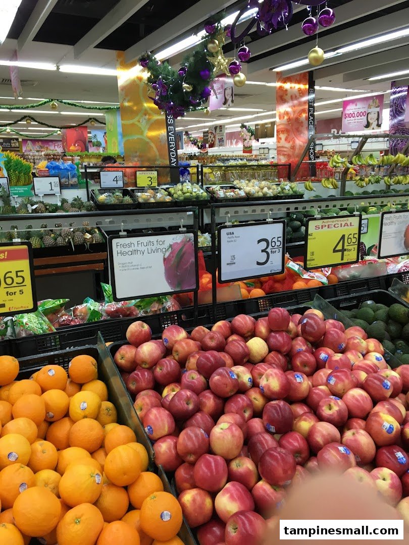 Vibrant display of fresh oranges and apples in a FairPrice supermarket aisle, featuring produce promotions.