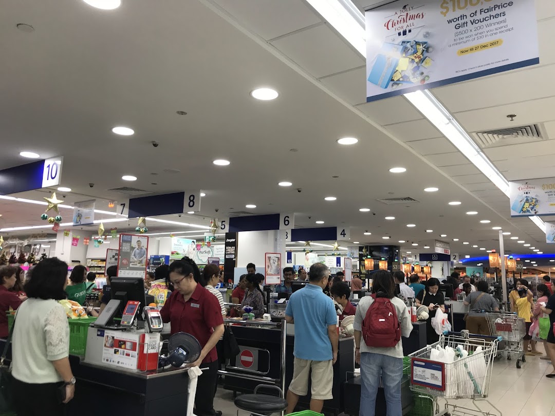 Busy checkout area of a FairPrice supermarket with customers and cashiers.