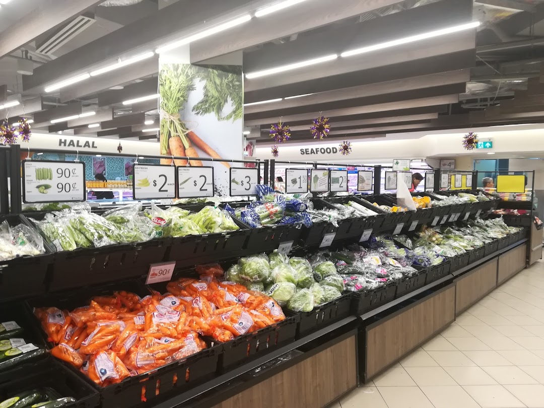A vibrant display of fresh produce, including carrots and leafy greens, in a well-stocked supermarket aisle.