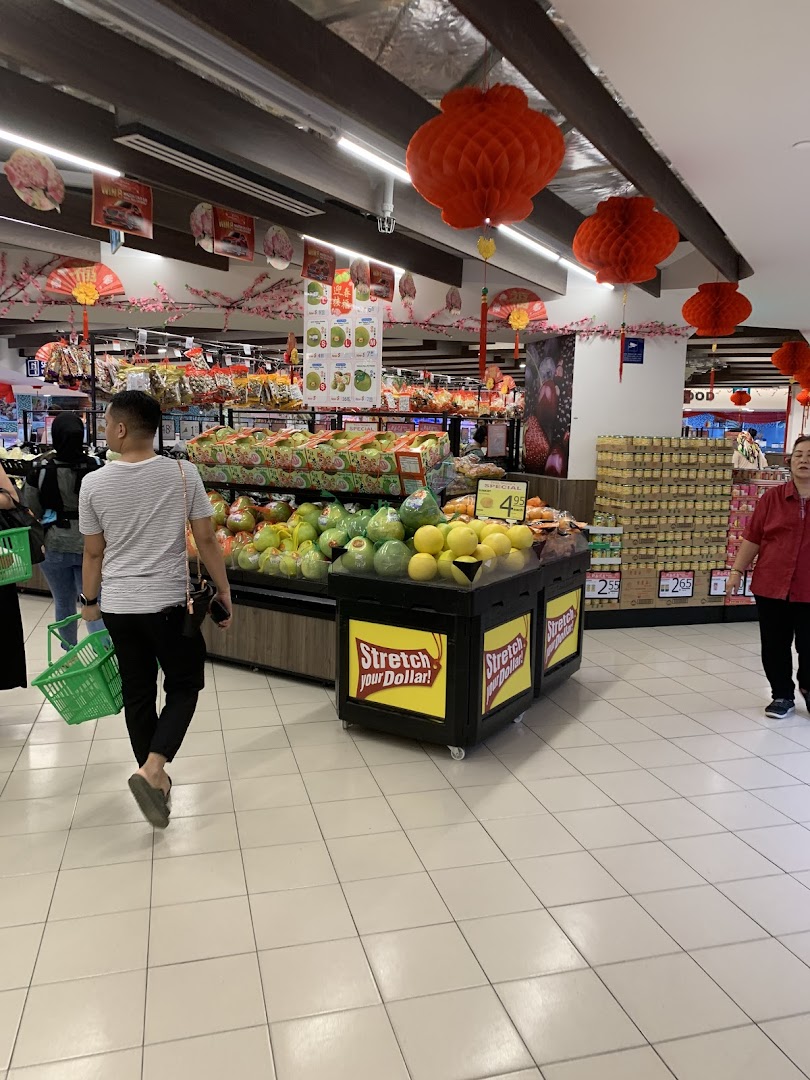Shoppers browse fresh produce and groceries in a brightly lit supermarket aisle adorned with festive red lanterns.