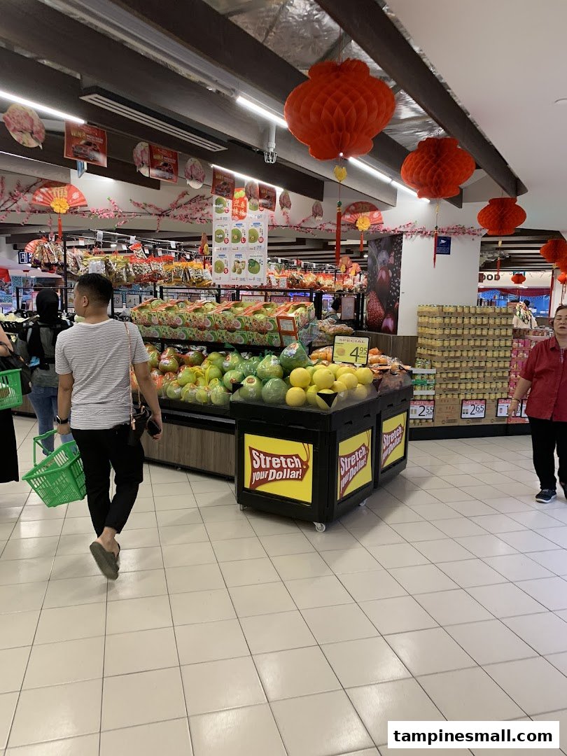 Shoppers browse fresh produce and groceries in a brightly lit supermarket aisle adorned with festive red lanterns.