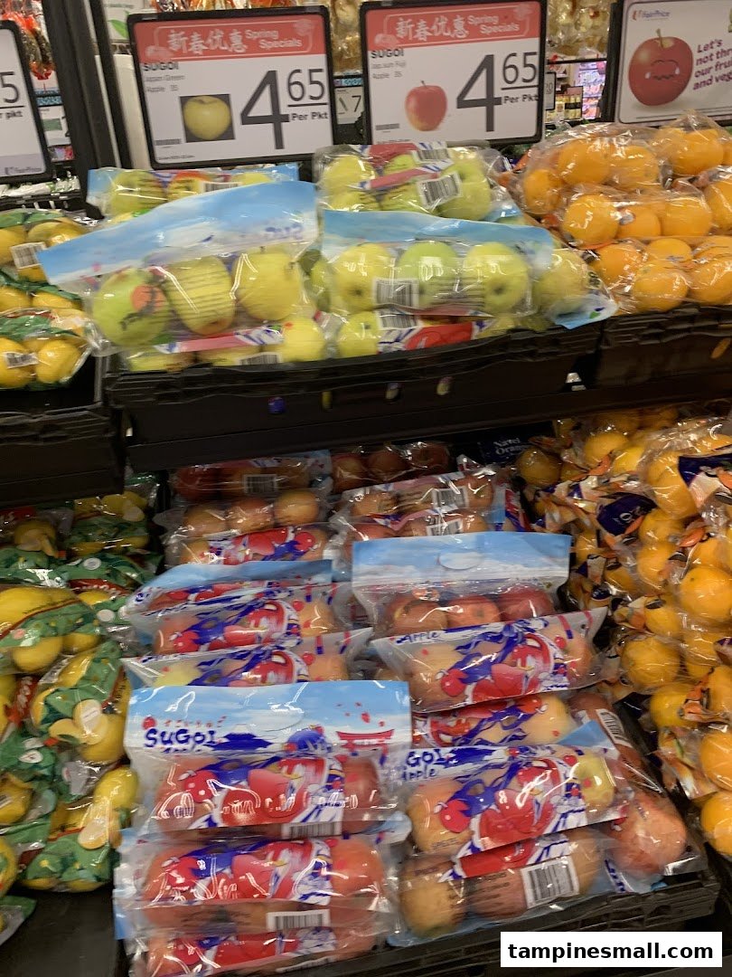 Packaged apples and citrus fruits displayed for sale with price signs in a supermarket.