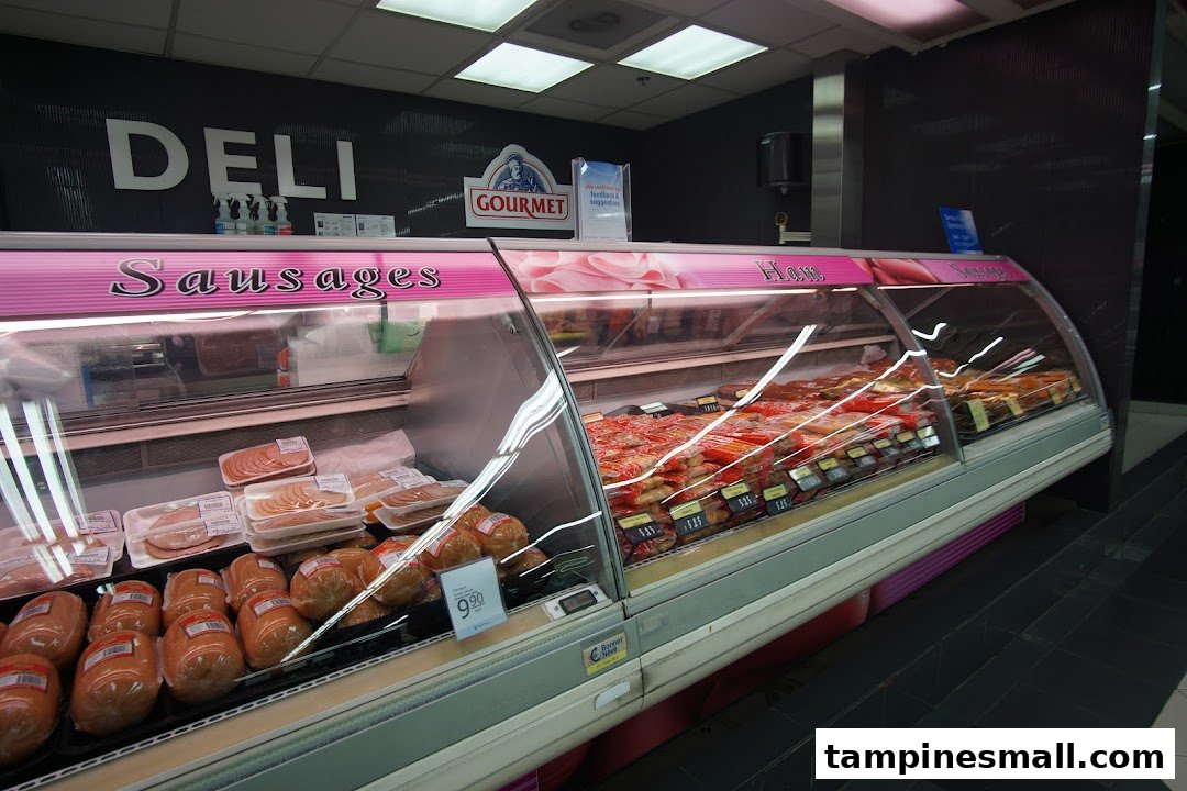A well-stocked deli counter at FairPrice Tampines Mall, featuring a variety of sausages and ham.