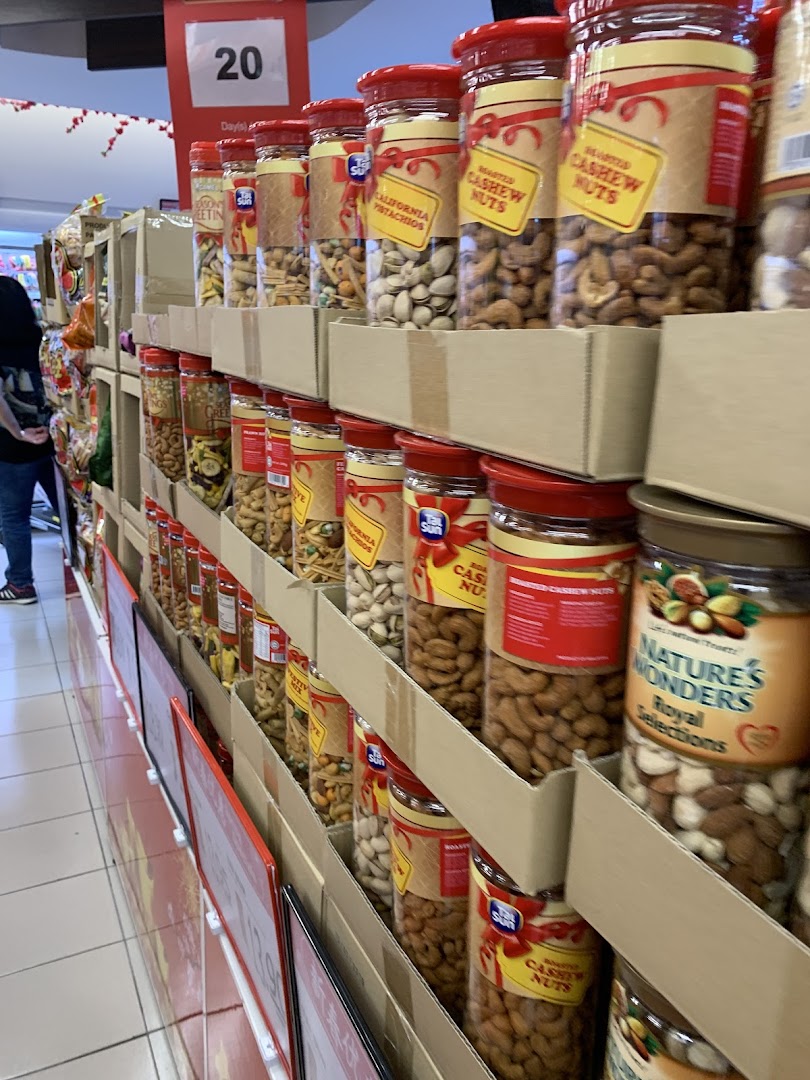 An aisle display at FairPrice Tampines Mall featuring various nuts and dried fruits in jars, including cashews and pistachios.