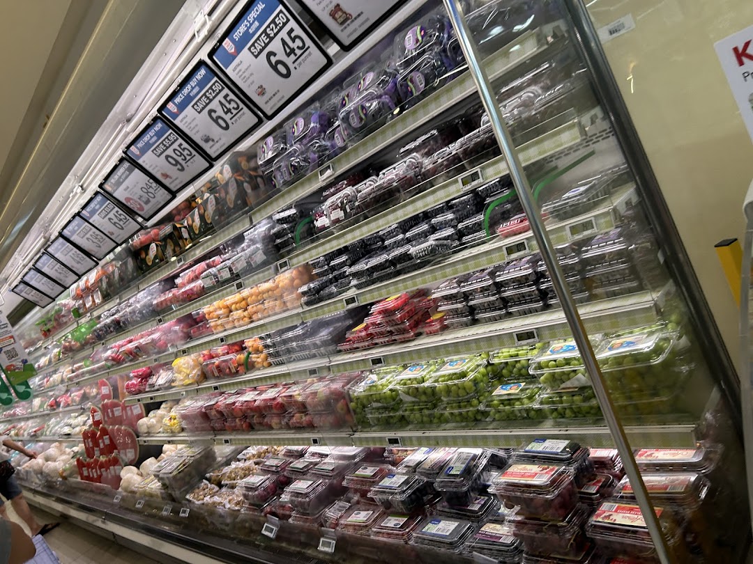 A refrigerated display case showcasing a wide variety of fresh fruits and vegetables at FairPrice Tampines Mall.