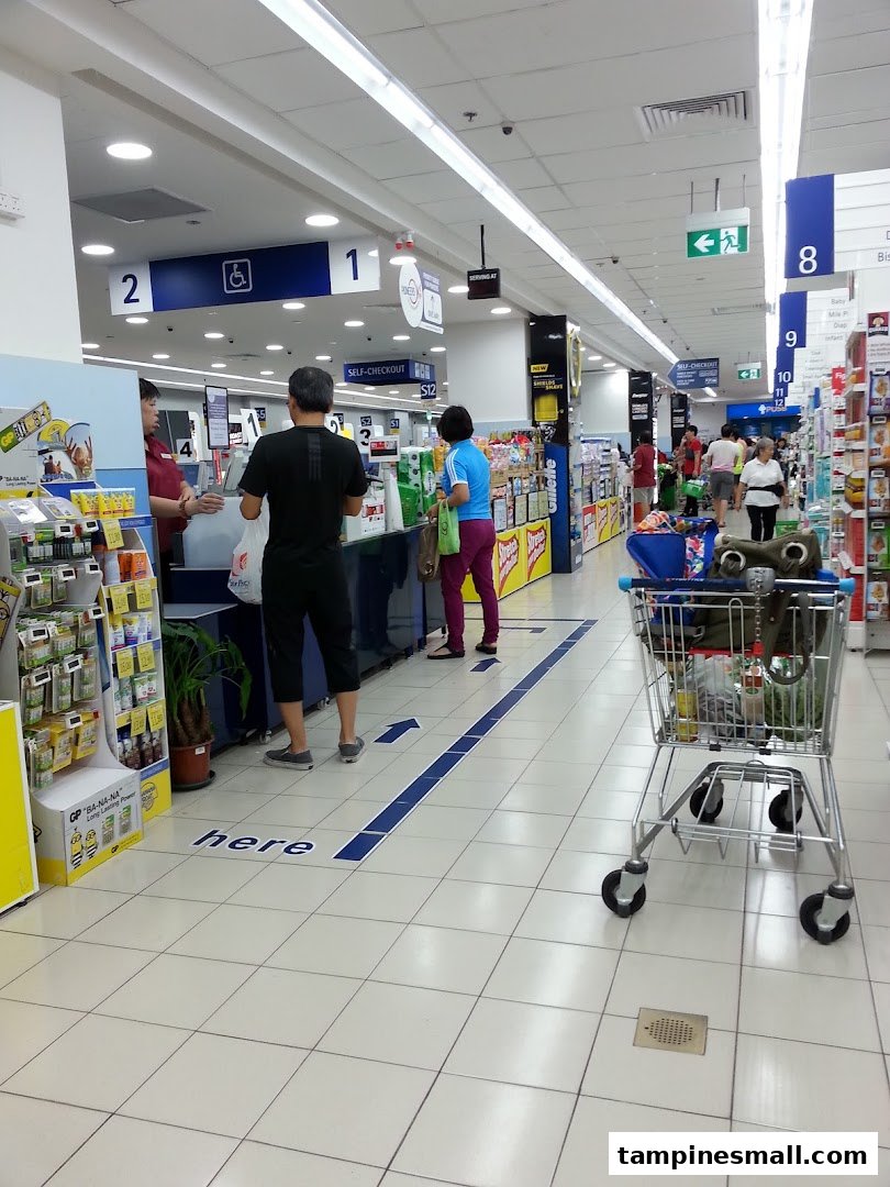 Customers queueing at the self-checkout and regular lanes inside a FairPrice supermarket.