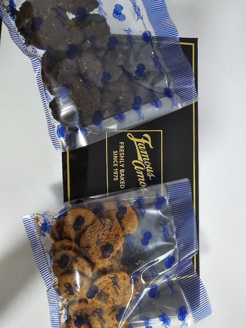 Two bags of Famous Amos cookies, chocolate chip and dark chocolate, on a black gift box.