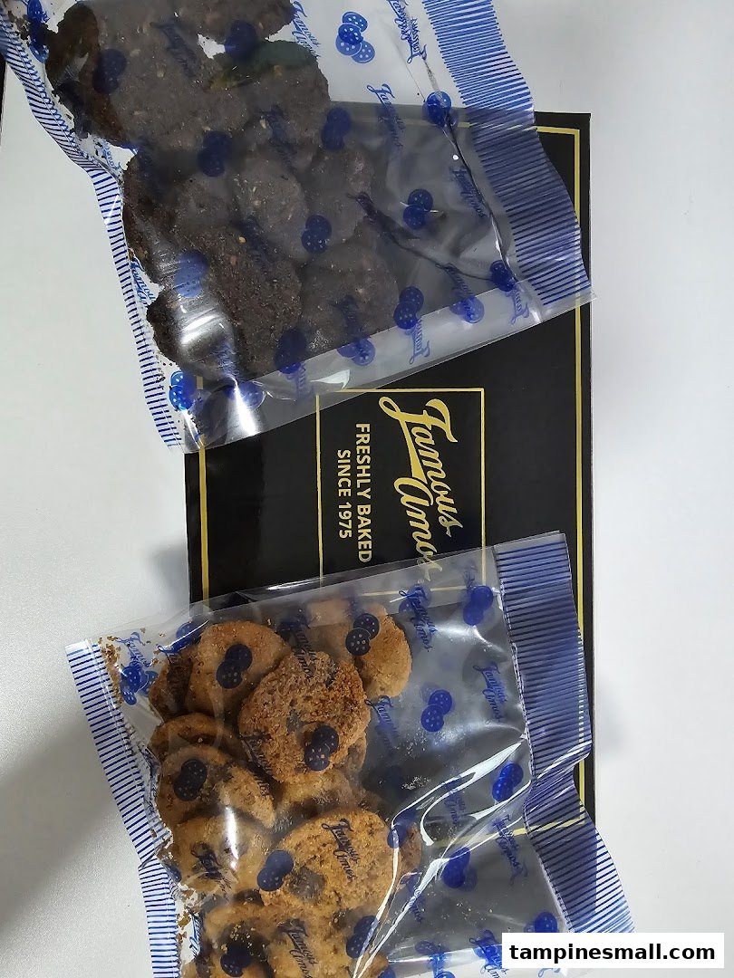 Two bags of Famous Amos cookies, chocolate chip and dark chocolate, on a black gift box.