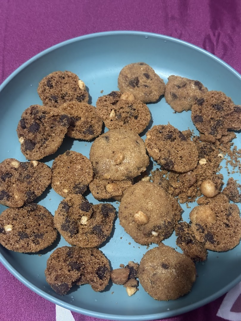 A blue plate filled with various Famous Amos cookies, including chocolate chip and nutty varieties.