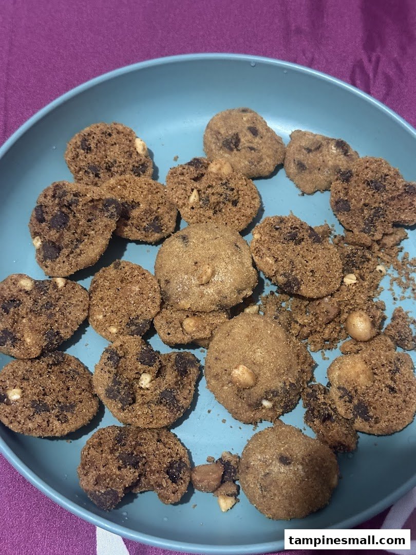 A blue plate filled with various Famous Amos cookies, including chocolate chip and nutty varieties.