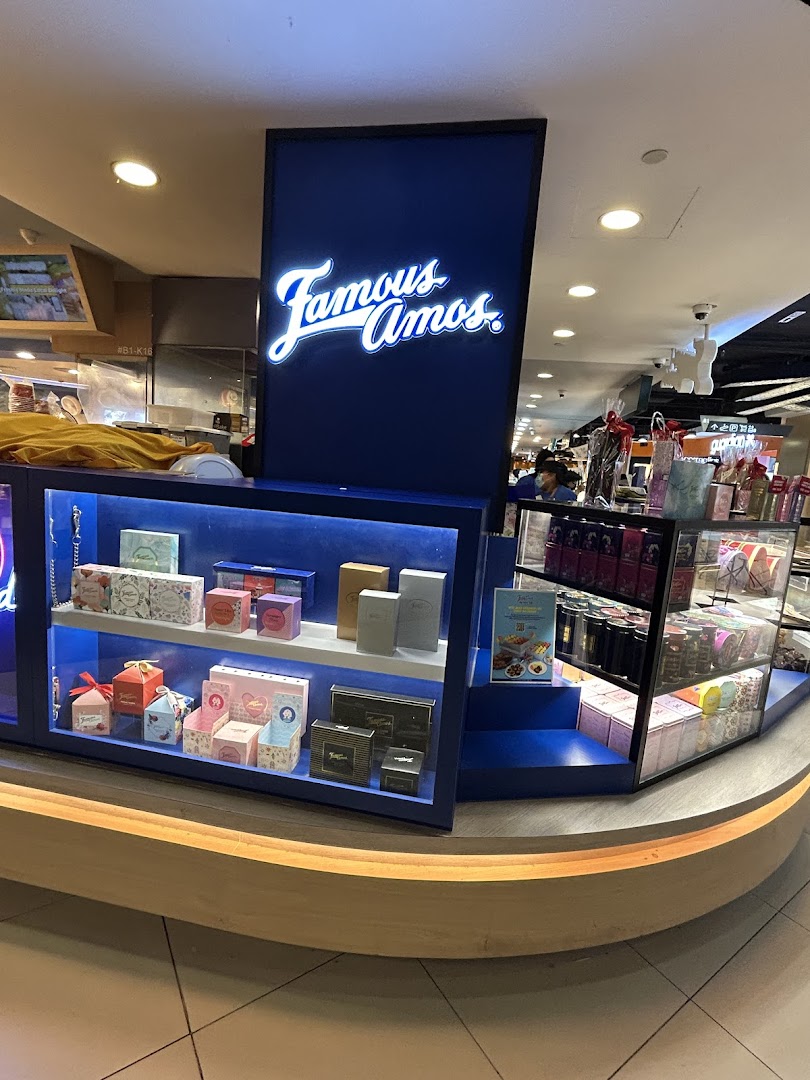 A Famous Amos kiosk displaying various cookie gift boxes and the brand's illuminated sign.
