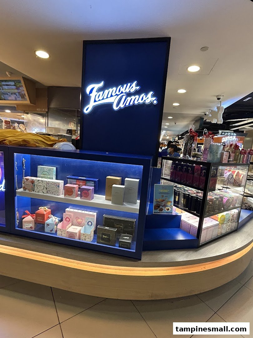 A Famous Amos kiosk displaying various cookie gift boxes and the brand's illuminated sign.
