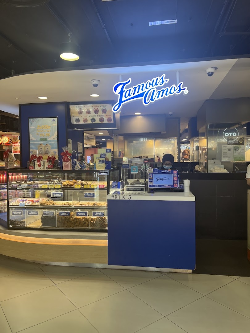 Famous Amos cookie shop front with display cases full of freshly baked cookies and a counter.