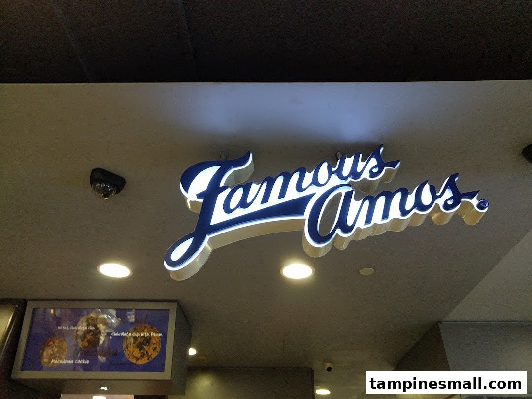 An illuminated 'Famous Amos' sign above a display showcasing various cookie flavors.