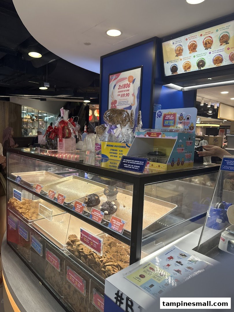 A display counter at Famous Amos showcasing various cookies, muffins, and promotional offers.
