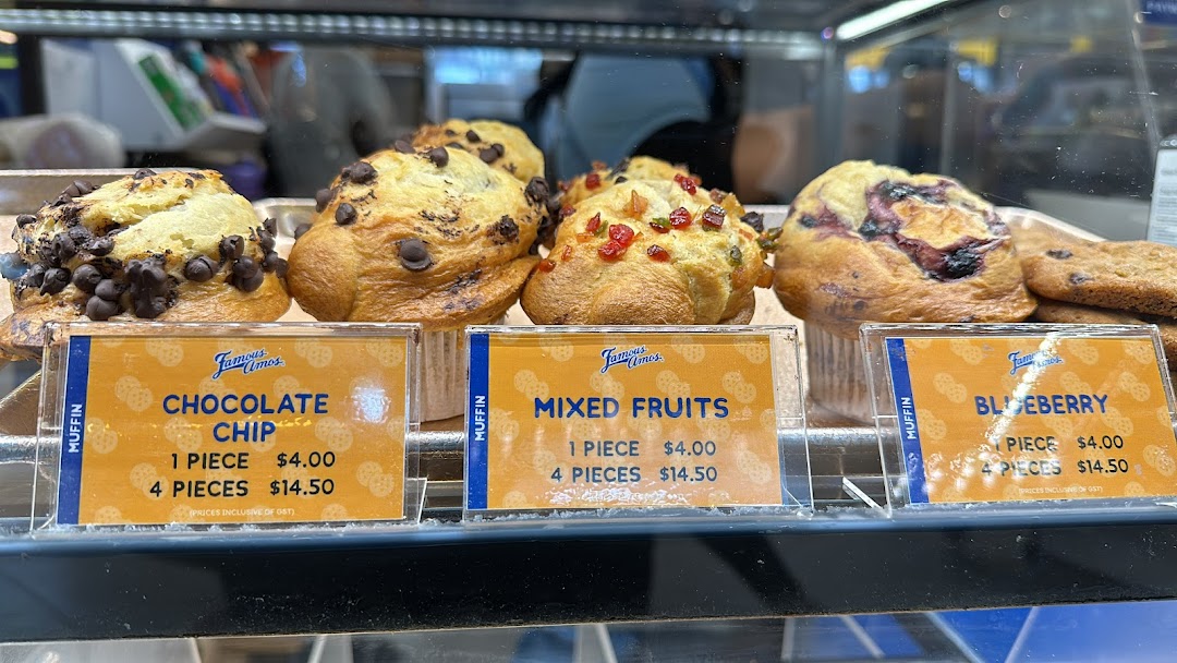 A display case showcasing various Famous Amos muffins with their prices.