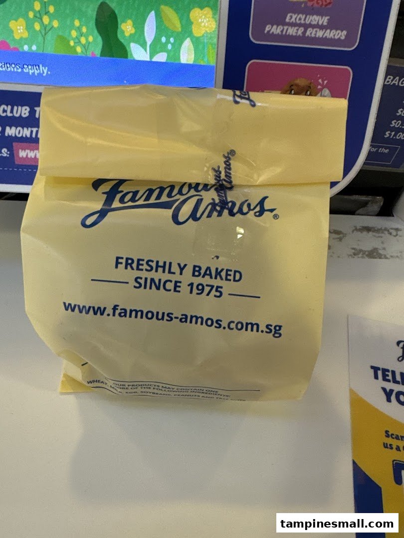 A yellow Famous Amos cookie bag displaying its logo, 'Freshly Baked Since 1975', and website.
