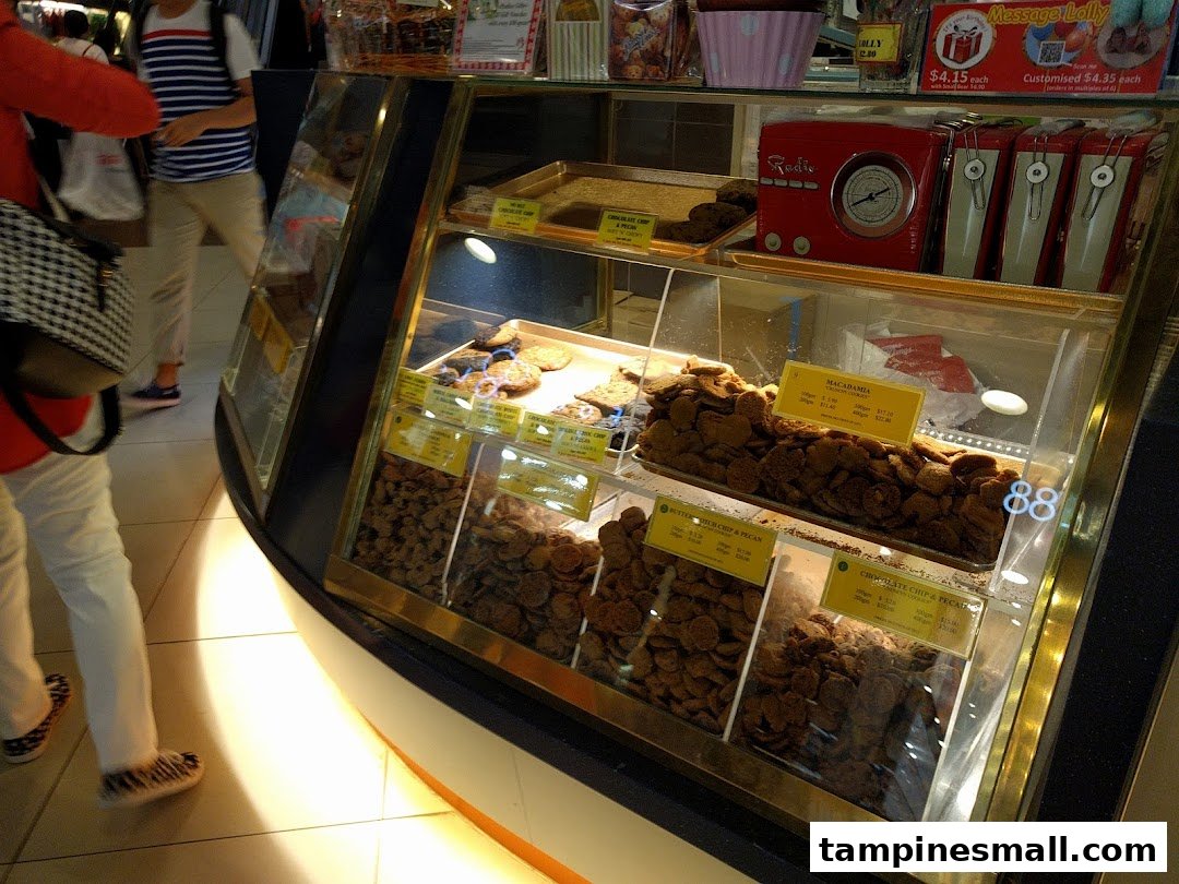 A glass display case at Famous Amos filled with various freshly baked cookies and merchandise.