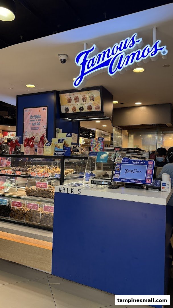 A vibrant Famous Amos cookie shop interior with display cases, counter, and prominent signage.