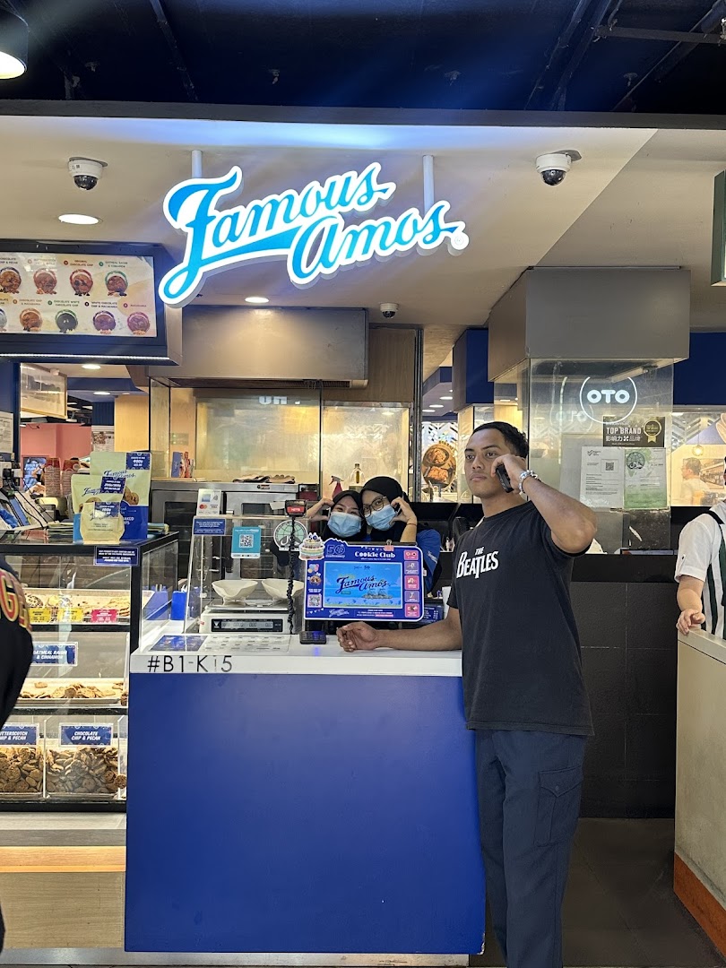 An interior view of Famous Amos, showcasing the counter, cookie displays, and staff.