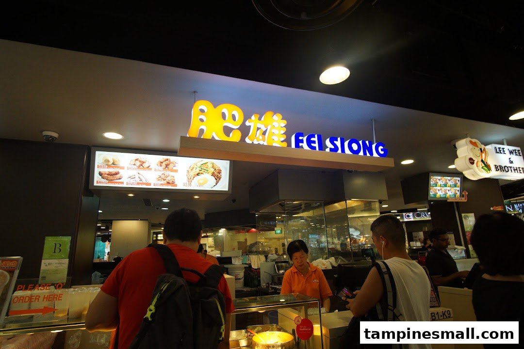 Customers ordering food at the Fei Siong food stall with staff and menu displays visible.