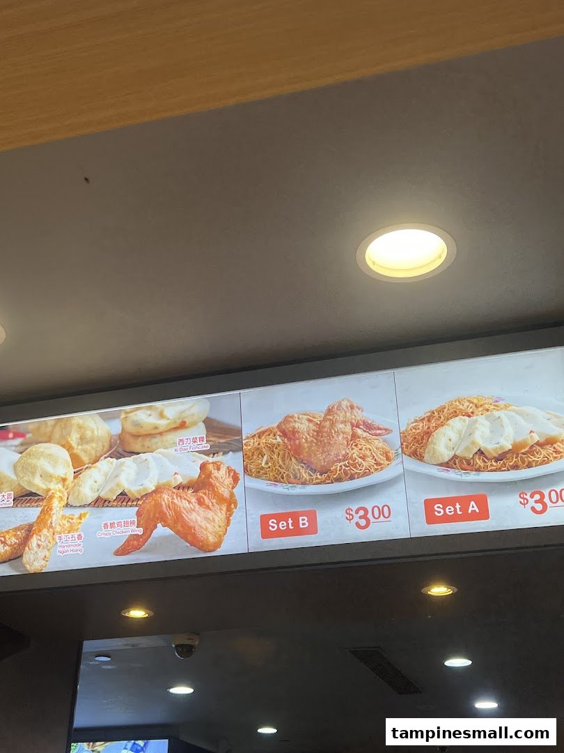 A digital menu board displaying various noodle sets and side dishes with prices.