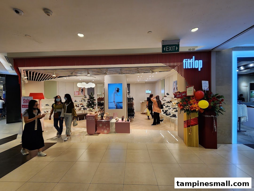 The image shows the inviting shop front of FitFlop Tampines, with customers browsing footwear and festive decorations.