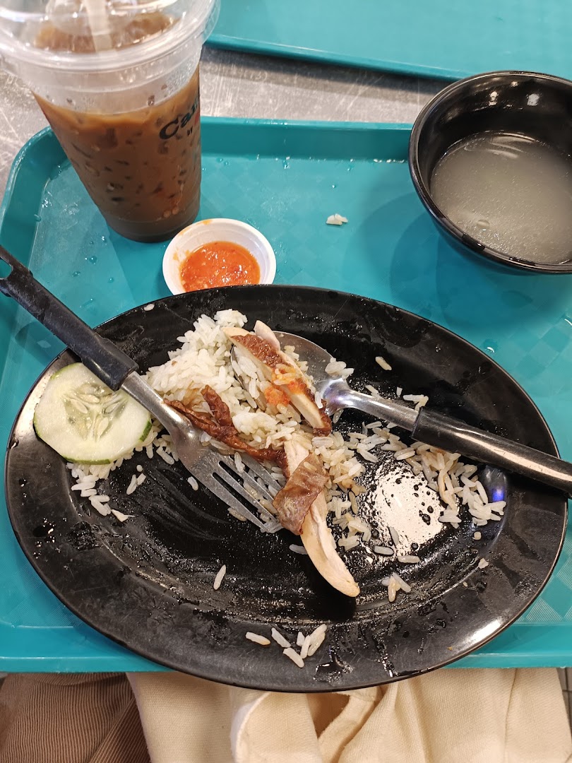 A partially eaten plate of chicken rice with a drink and soup on a blue tray.
