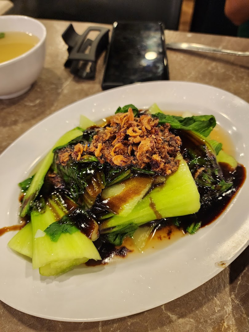 A plate of vibrant green bok choy with savory sauce and crispy fried toppings, served with soup.