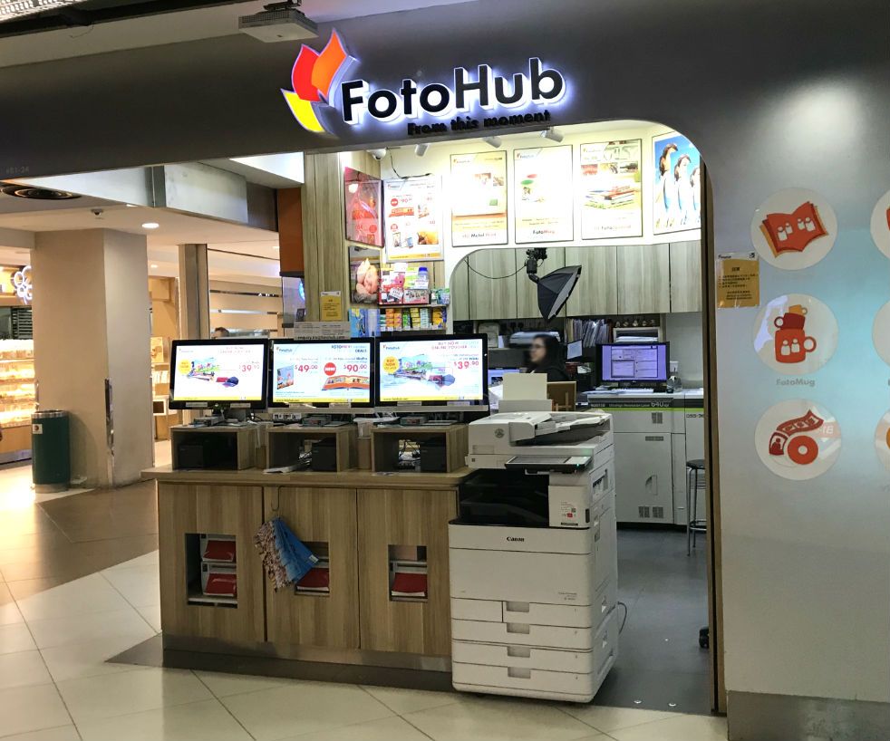 FotoHub shop entrance featuring self-service kiosks, printing equipment, and vibrant signage.