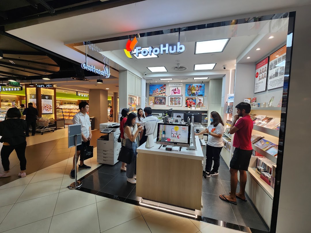 Customers interact with staff and kiosks at FotoHub, a photo printing and imaging service shop.