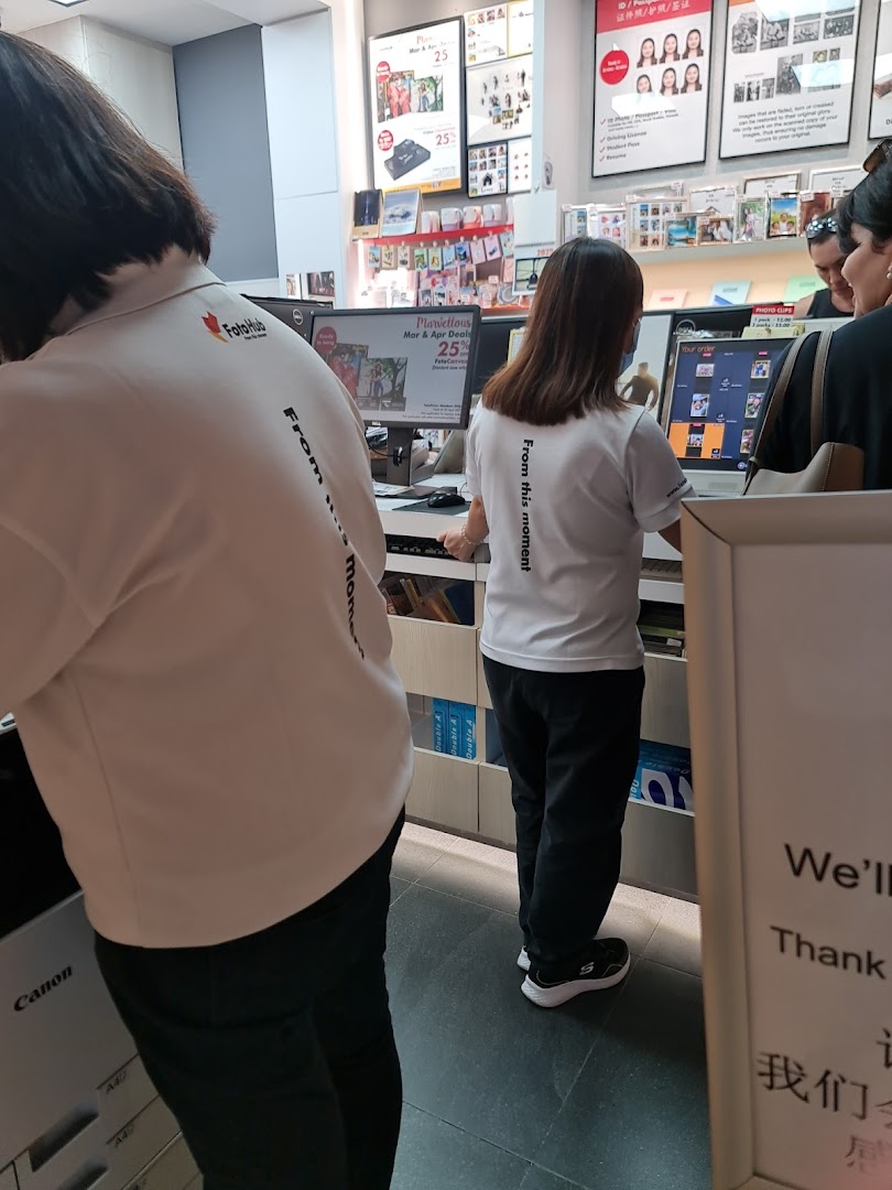 FotoHub staff assist customers at service counters for photo printing and imaging services.
