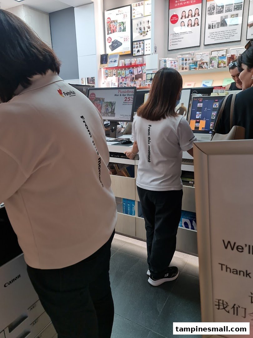 FotoHub staff assist customers at service counters for photo printing and imaging services.