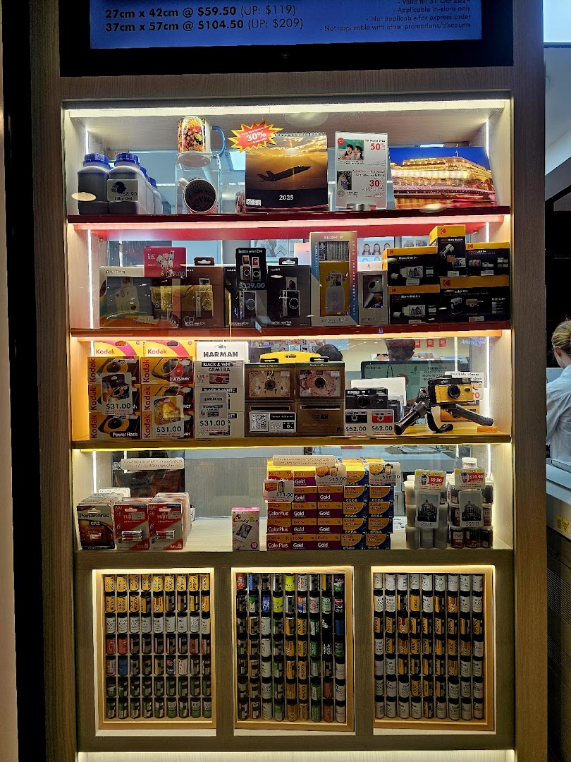 A brightly lit display of camera film, disposable cameras, and photo printing merchandise at FotoHub.