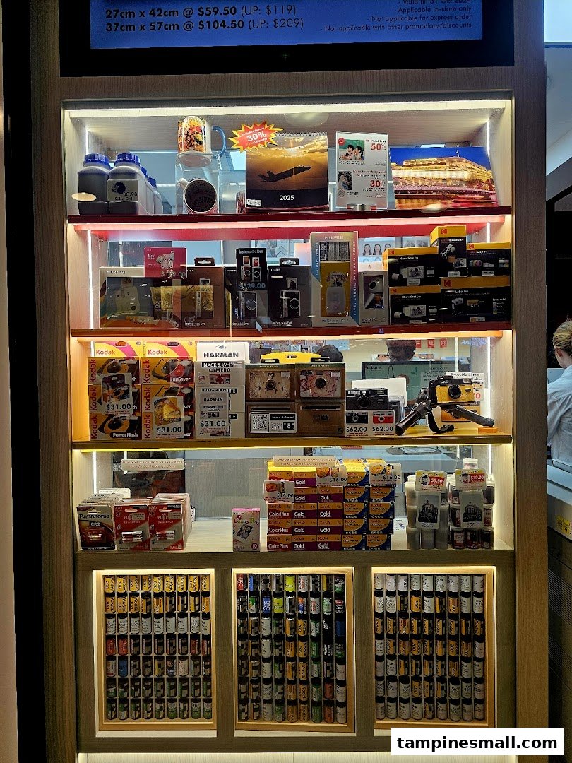 A brightly lit display of camera film, disposable cameras, and photo printing merchandise at FotoHub.