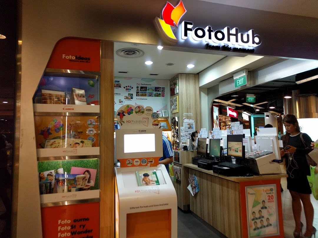 The FotoHub shop front in Tampines Mall, showcasing photo printing services and product displays.
