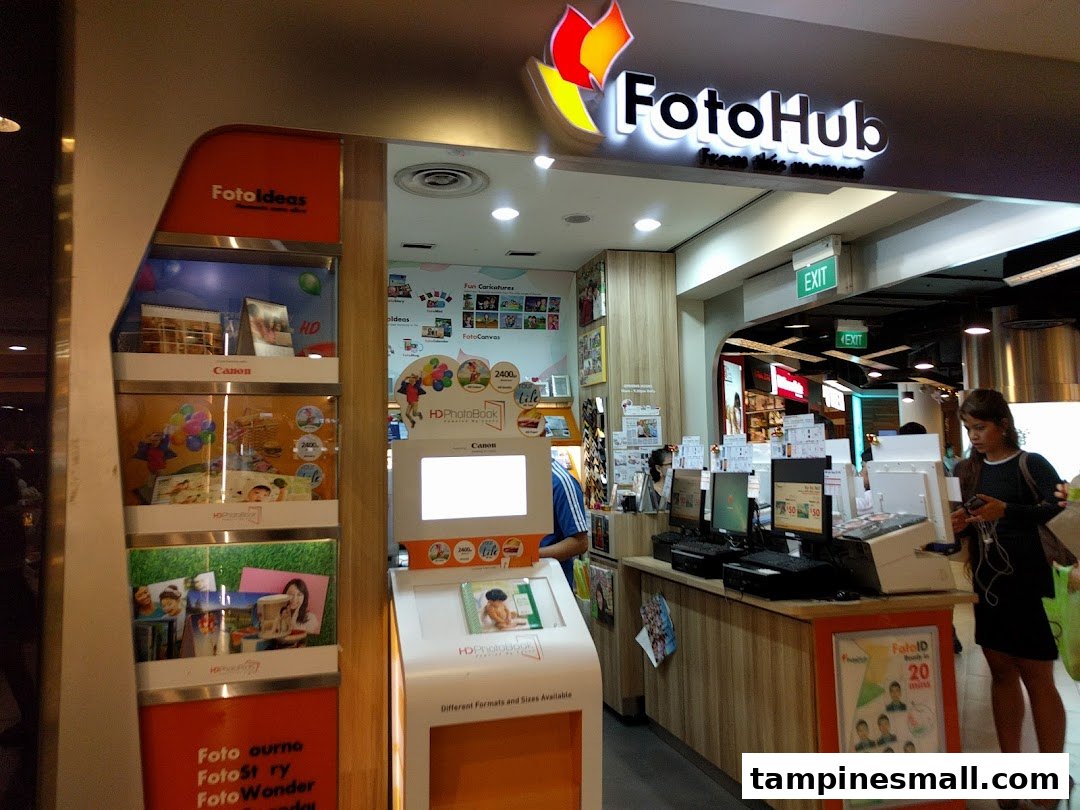 The FotoHub shop front in Tampines Mall, showcasing photo printing services and product displays.