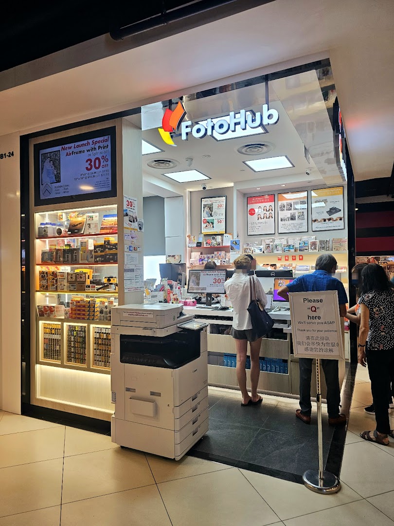 The FotoHub shop entrance with customers, product displays, and promotional signage at Tampines Mall.