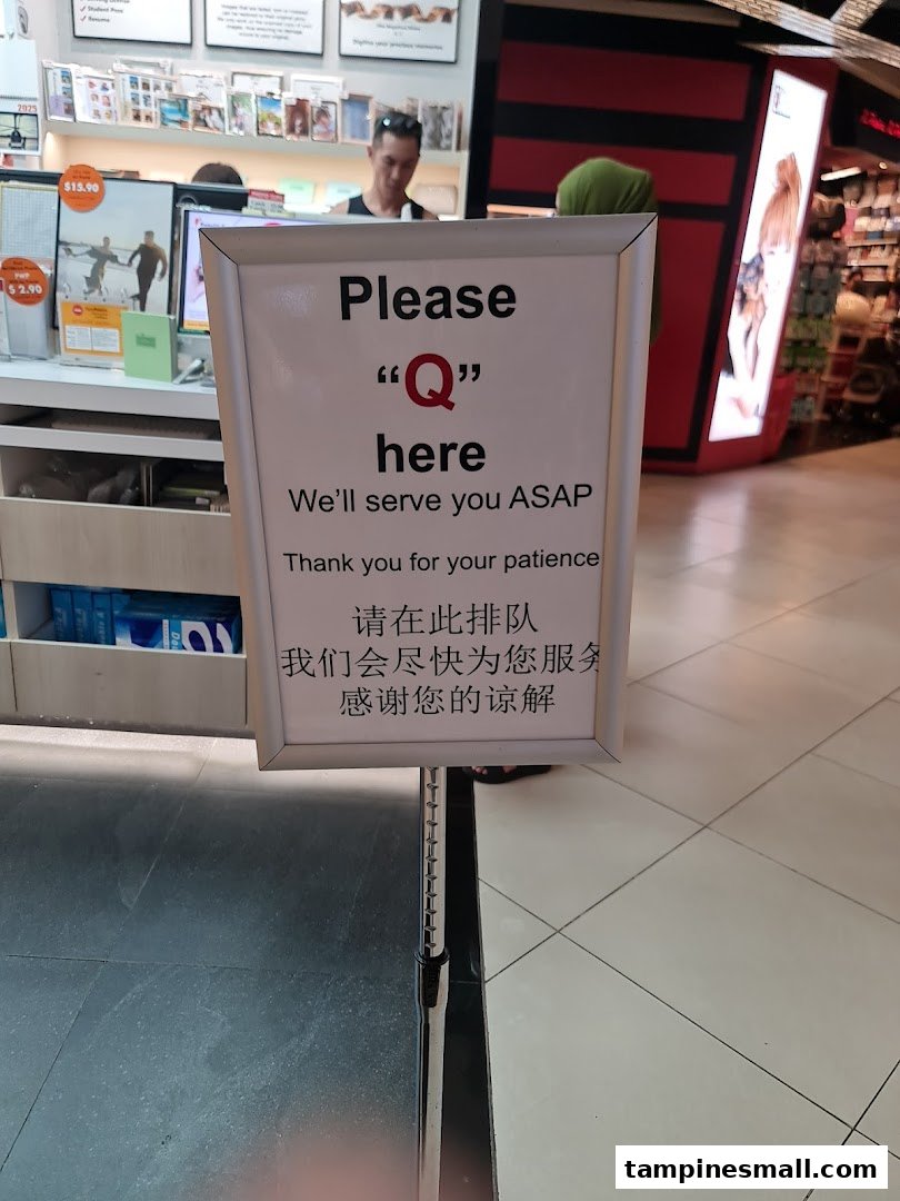 An interior shot of FotoHub showing a 'Please Q here' sign and a service counter.