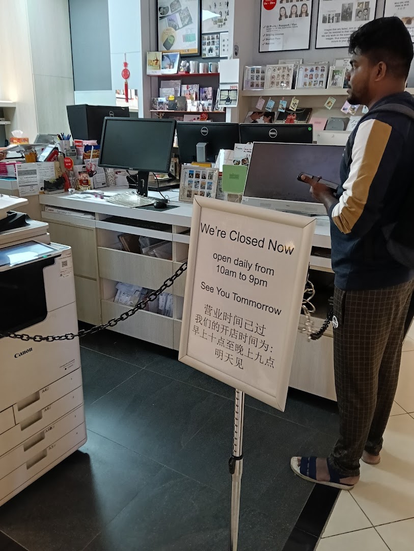 Interior view of FotoHub with a 'Closed Now' sign, showing the service counter and a customer.