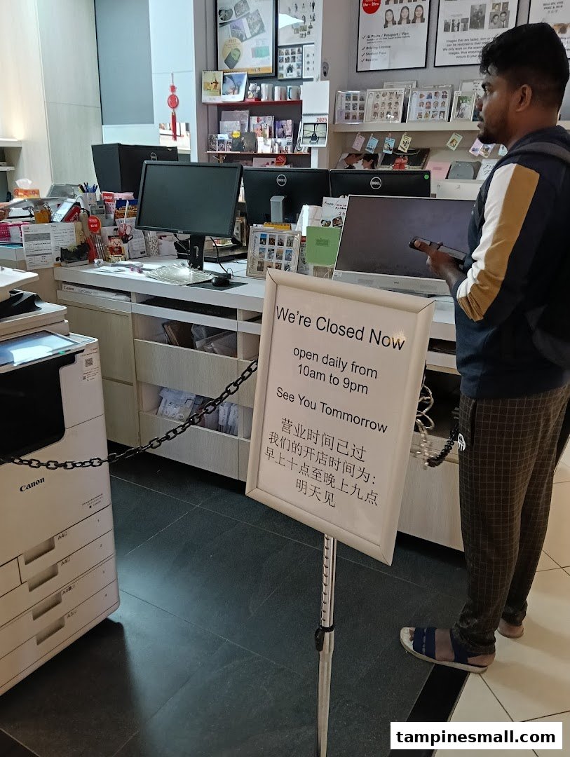 Interior view of FotoHub with a 'Closed Now' sign, showing the service counter and a customer.