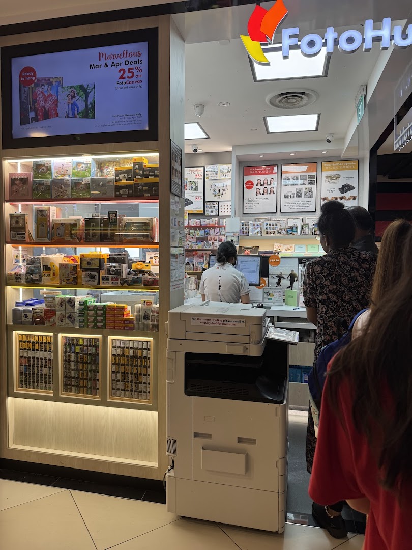 FotoHub shop front with digital displays, product shelves, and customers at the counter.