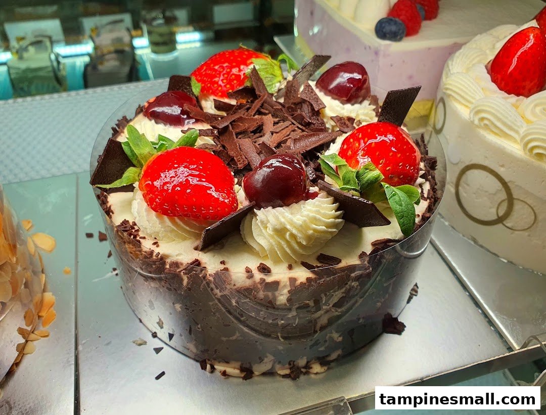 A decadent chocolate cake topped with fresh strawberries, cherries, and chocolate shavings.